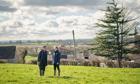 a couple of men standing in a field with a building in the background